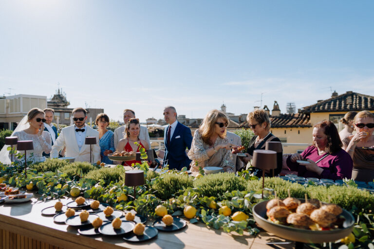 Terrace celebration in Rome, guests chatting and laughing during aperitivo