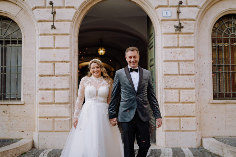 Bride and groom exiting a historic building in Tivoli, Italy.