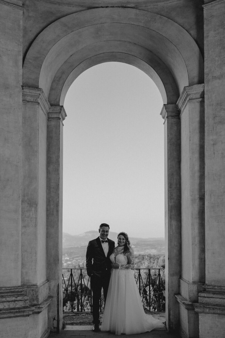 Bride and groom framed by an archway in Tivoli, Italy, cinematic composition.