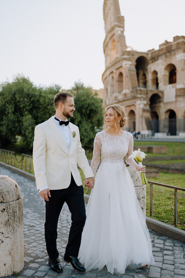 Couple walking together in Rome with the Colosseum in the background.