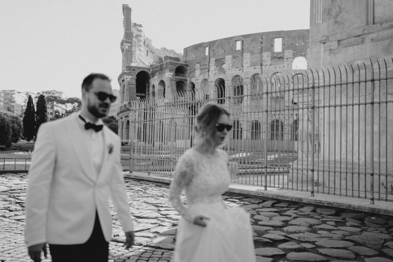 Black and white couple walk in Rome, Colosseum view behind.