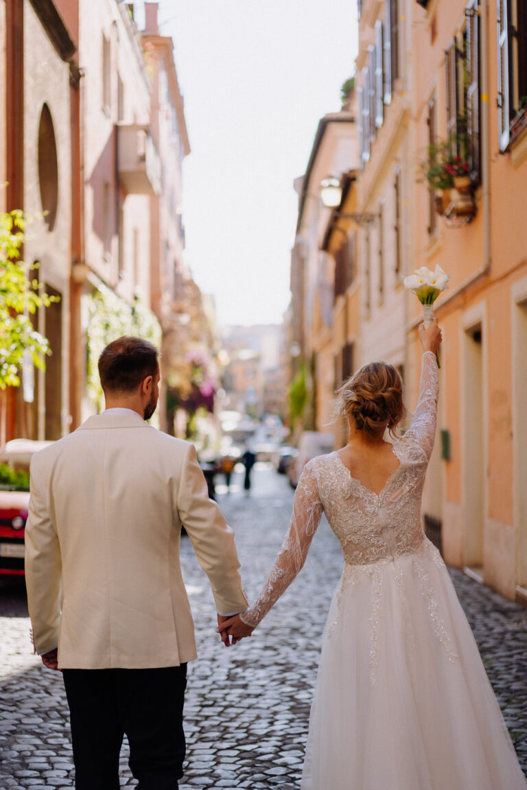 Bride and groom walking through a Rome street, candid moment from behind
