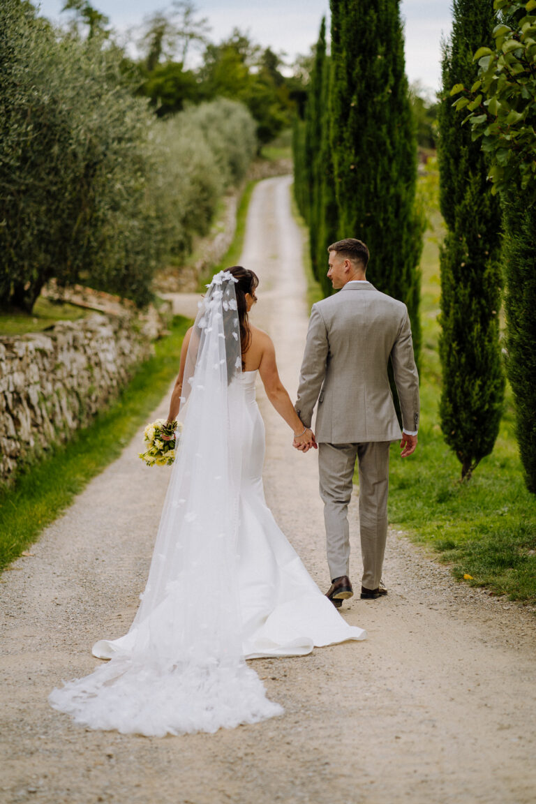 Bride and groom walking away together, Chianti countryside.