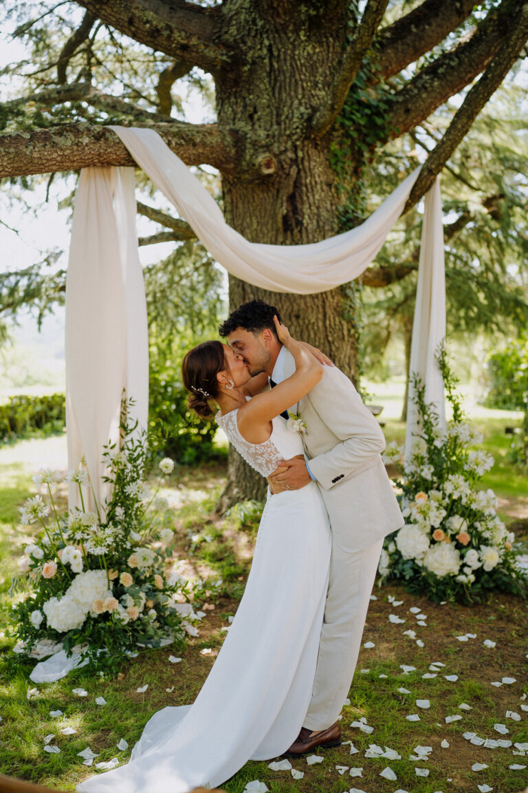Couple kiss under trees after ceremony, Tuscany